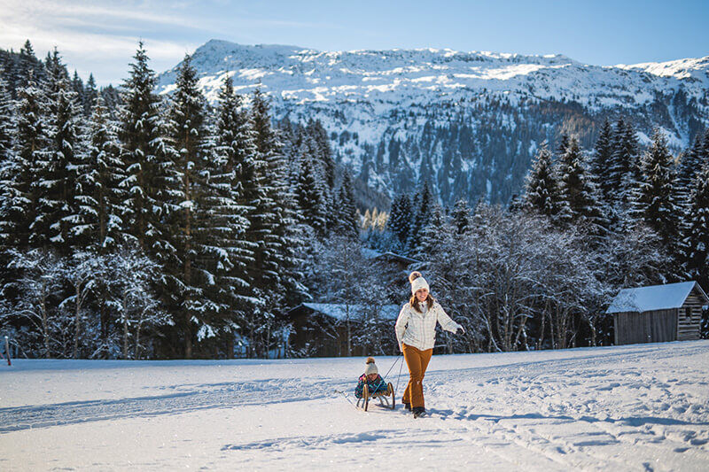 Bergdorf-Prechtlgut-Wagrain-Familienluxusreisen-Frau-mit-Schlitten