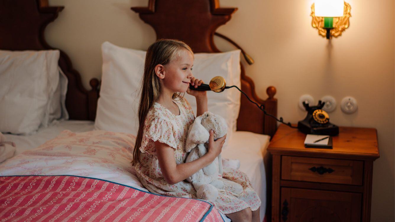 Goldener Hirsch Mädchen sitzt auf dem Bett und symbolisiert telefonieren