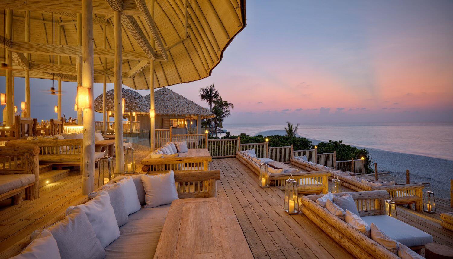 Lounge mit gemütlichen Sitzbänken und Blick aufs Meer bei untergehender Sonne