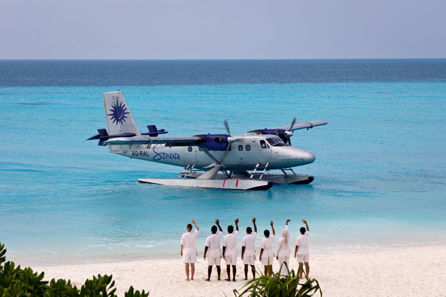 Angestellte eines Resorts winken einem Wasserflugzeug am Strand zu