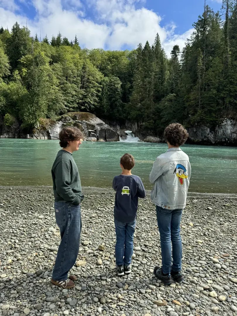 Drei Brüder stehen an einem Flussbett in der unberührten Natur Kanadas