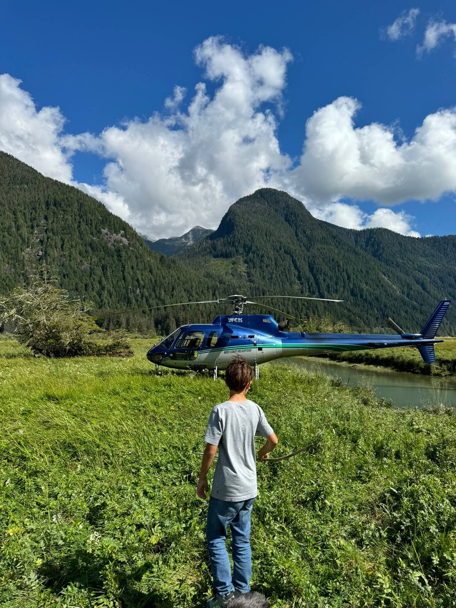 Ein Junge läuft auf einen Helikopter zu, der auf einer Wiese steht.