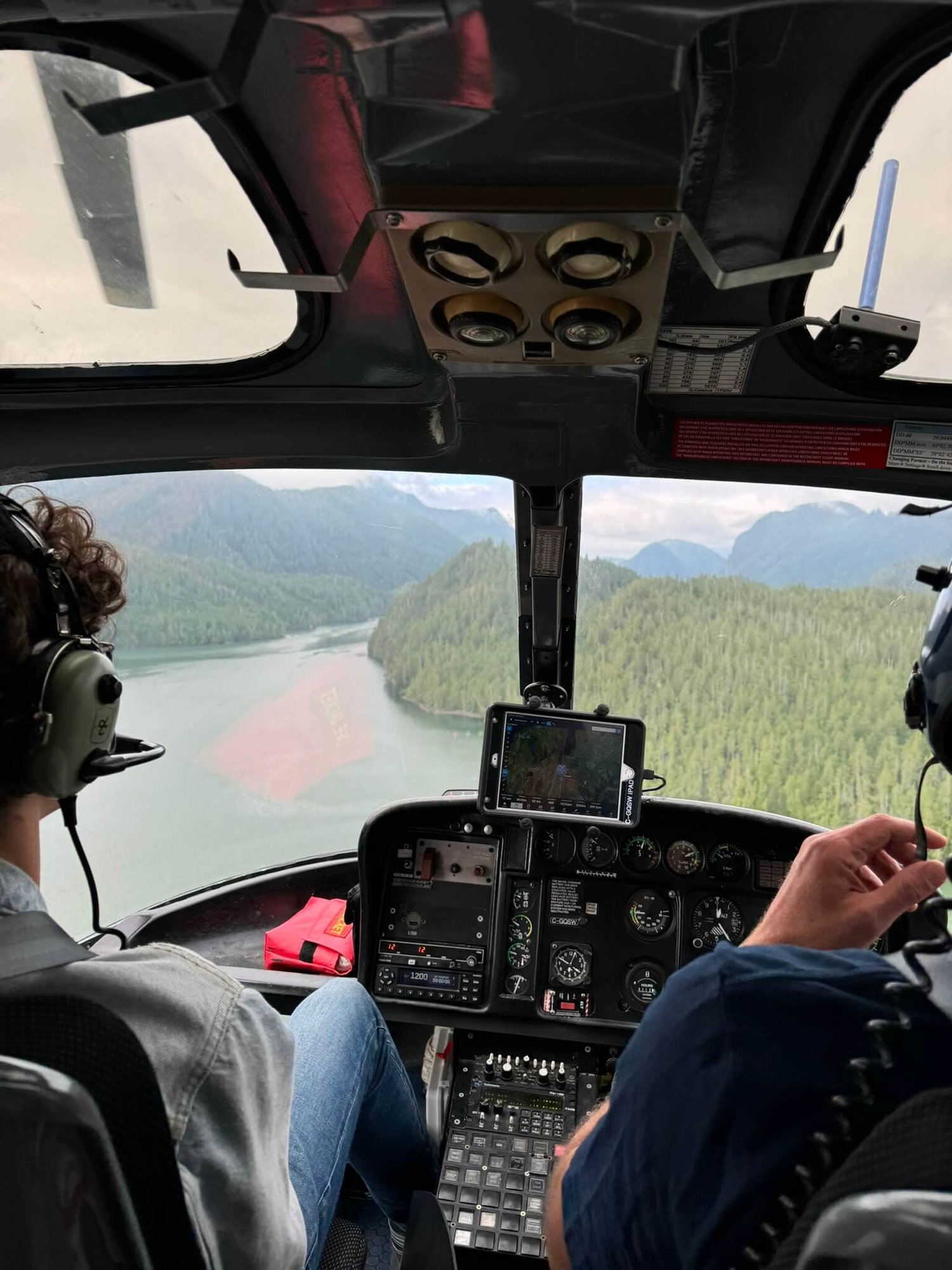 Blick aus einem Helikopter-Cockpit auf die grüne Landschaft Kanadas.
