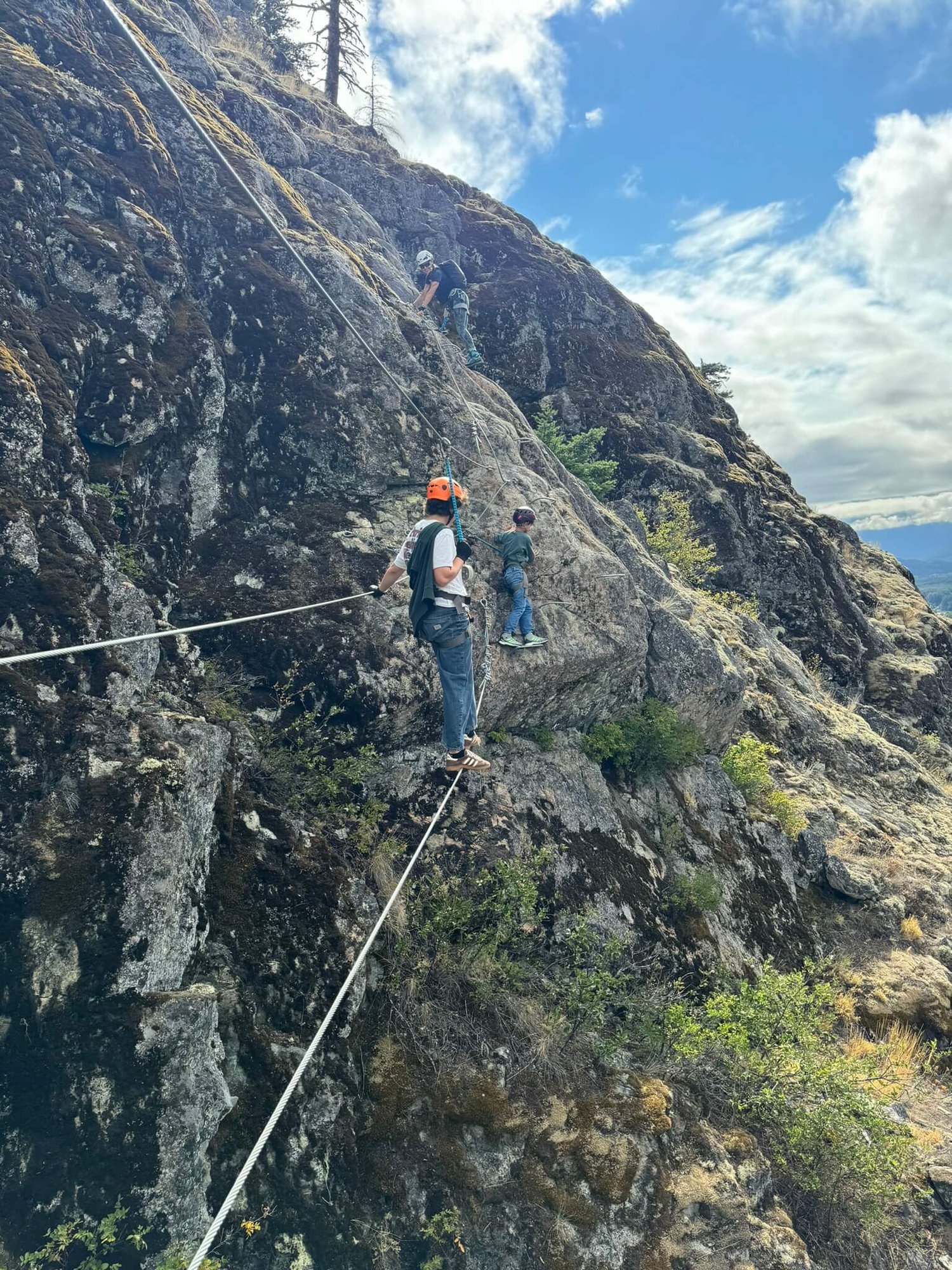 Eine Schlucht ist mit Kletterseilen überspannt, über die sich ein Teenager hangelt.