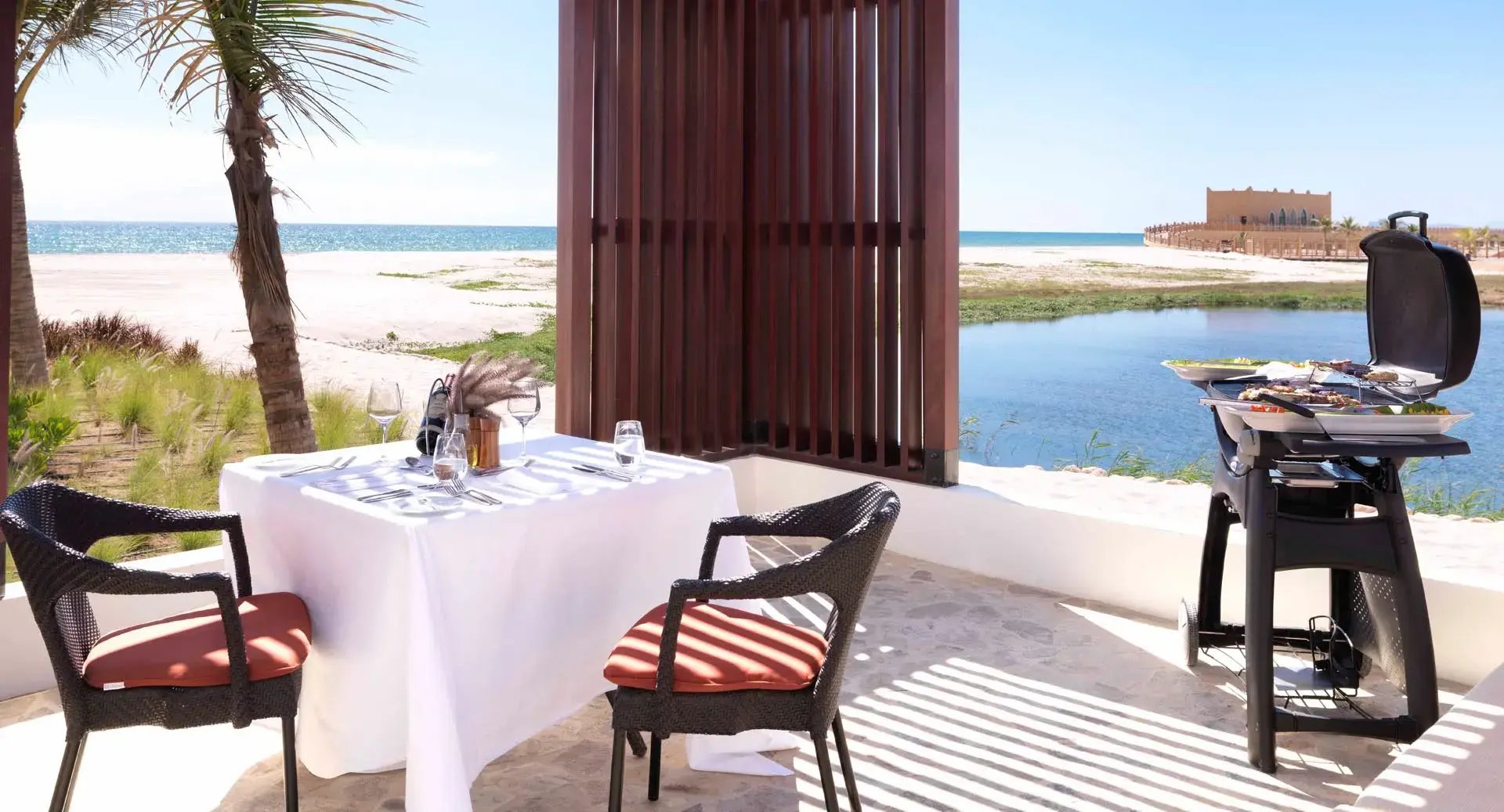 Kleiner Tisch am Strand, neben dem ein Grill steht.