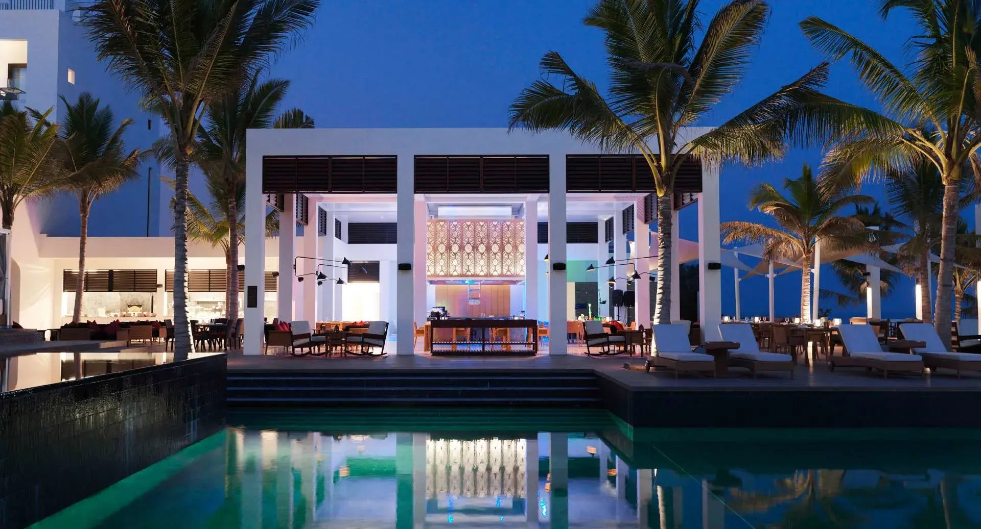 Beleuchtetes Restaurant mit Pool eines Resorts.