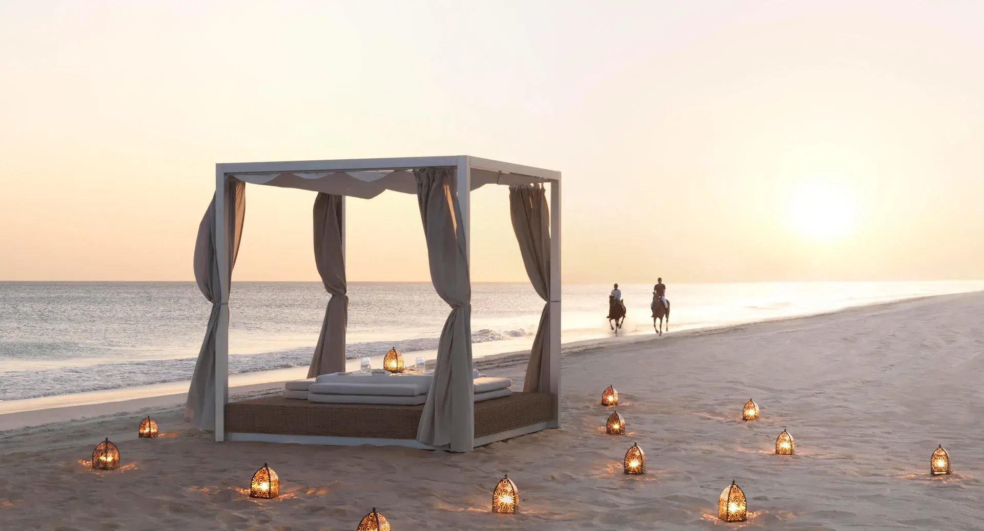 Tagesbett am Strand umgeben von vielen Laternen.