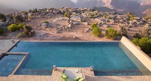 Infinity Pool mit Blick in die raue, felsige Landschaft des Omans.