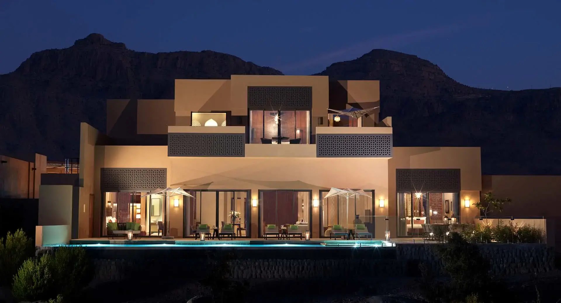 Beleuchtete Villa mit Pool am Abend.