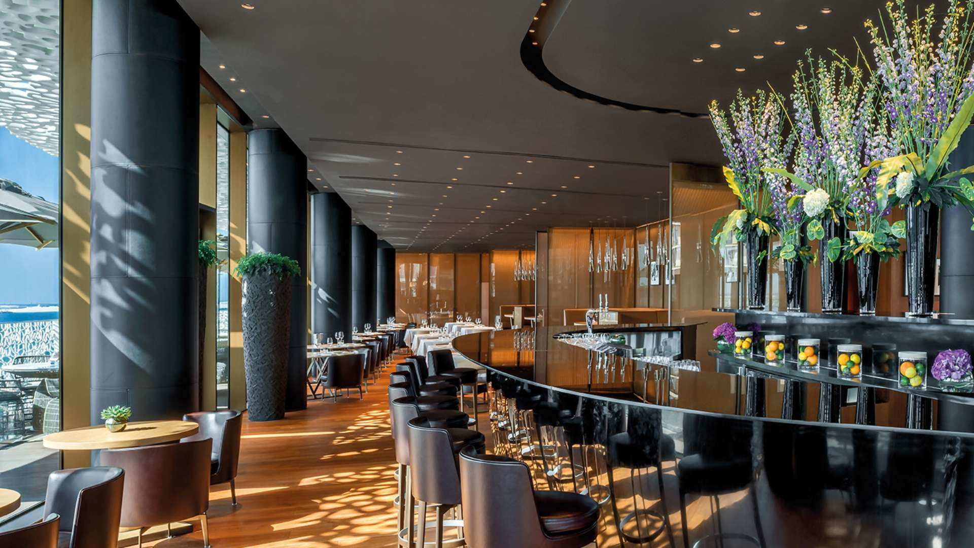 Stylische Bar mit großen Säulen und Fensterfronten.