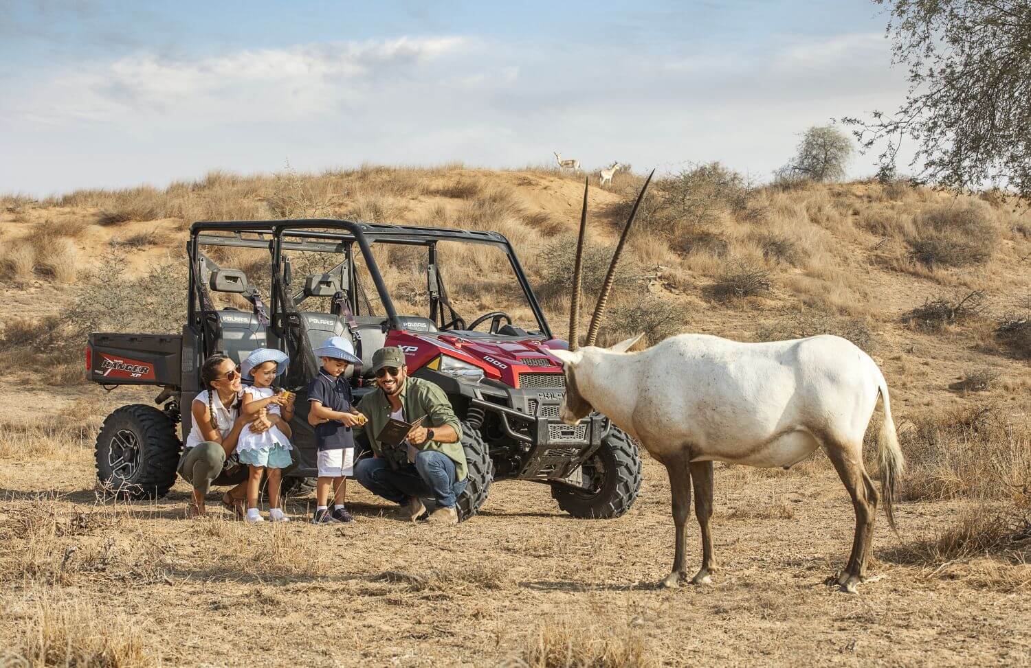 Eine Familie steht in der Wildnis vor einer weißen Oryxantilope.