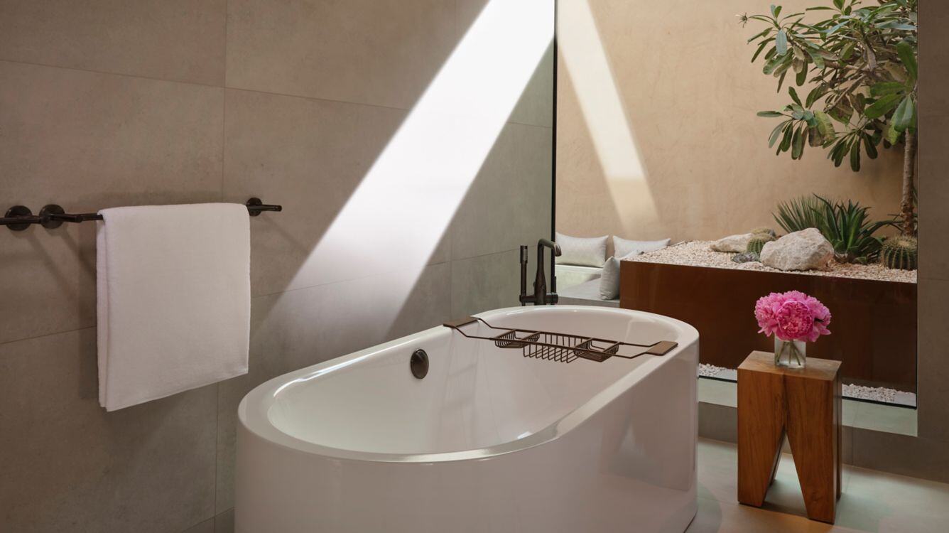 Weiße Badewanne neben der eine Blume steht.