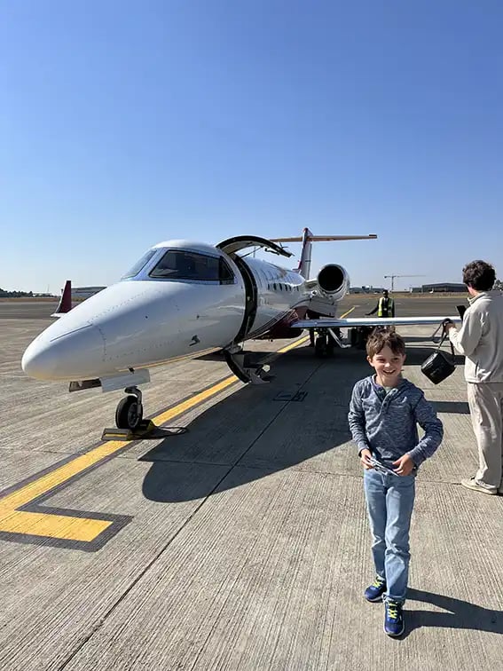 Ein kleiner Junge steht auf der Landebahn vor einem Privatjet